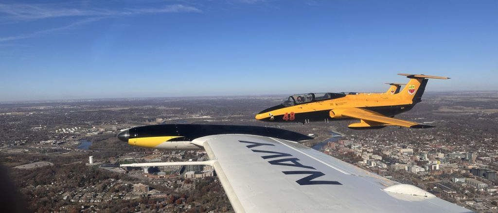 Yellow military training aircraft flying alongside a commercial passenger aircraft